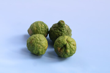 Fototapeta premium Fresh kafir limes display vibrant green color and unique bumpy texture, showcasing their natural beauty. These limes are often used in culinary dishes and traditional remedies