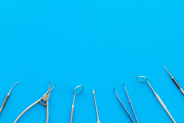 Stomatological tools on dentist's desk on blue background top-down pattern frame copy space