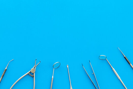 Stomatological tools on dentist's desk on blue background top-down pattern frame copy space