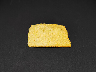 Golden Crispy Snack Piece on Dark Background
