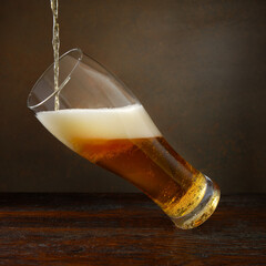Beer. Jet of beer is poured into a beer glass, causing a lot of bubbles and foam