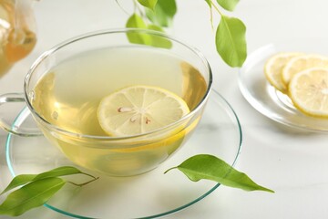Refreshing green tea with lemon and leaves on white marble table, closeup