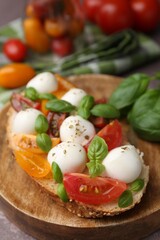 Tasty sandwich with mozzarella cheese, tomatoes and basil on brown table, closeup