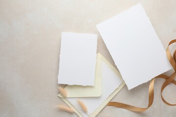 Wedding invitation cards, envelope, ribbon and spikelets on color textured table, flat lay. Space...