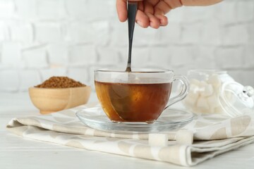 Woman making instant coffee at light table, closeup