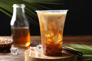 Tasty iced bubble tea and ingredients on wooden table, closeup