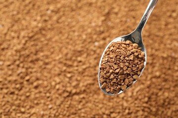 Spoon with aromatic instant coffee as background, closeup