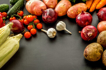 Set of autumn vegetables - potato, cucumber, carrot, greenery - on black background copy space