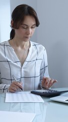 Female professional calculating finances, reviewing paperwork, tracking business expenses with...