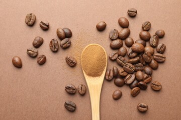 Spoon with instant coffee powder and beans on beige background, flat lay
