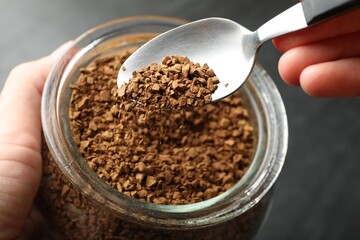 Woman taking instant coffee from jar at table, closeup