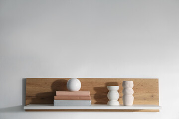 Wooden shelf with books and decor on white background. Space for text