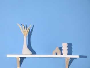 Shelf with beautiful decor on blue background. Space for text