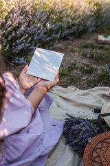 Girl holding blank white card in lavender field, wearing lilac dress. Perfect mockup for branding...