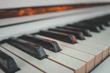 Close-up of vintage white piano keys in soft light. Focus on black and white keys with shallow...