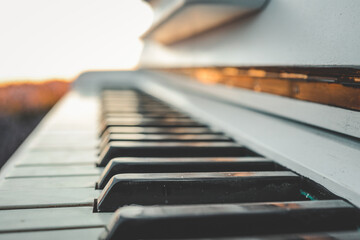Close-up of piano keys with soft sunset light. Artistic shallow focus on black and white keys,...