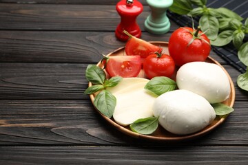 Tasty mozzarella cheese, tomatoes, basil and spices on wooden table, closeup. Space for text