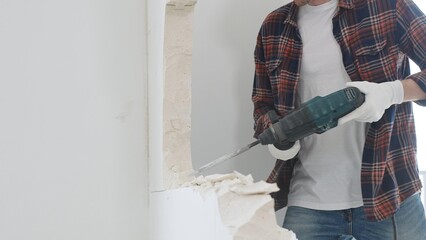 Unknown male construction worker wearing red checkered shirt jeans and protective gloves, is...