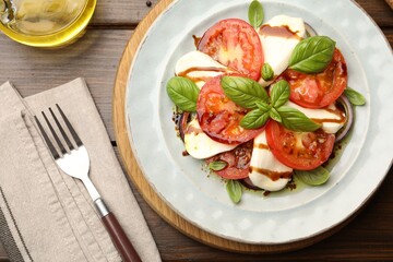 Tasty salad Caprese served with balsamic vinegar on wooden table, flat lay