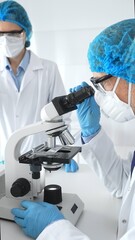 Two scientists, a man and a woman, wearing blue protective hairnets, masks and protective glasses,...