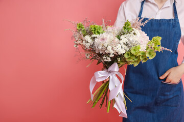 Florist with beautiful bouquet of flowers on pink background, closeup. Space for text