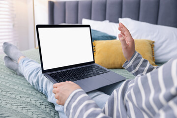 Woman having online consultation with doctor via laptop on bed at home, closeup