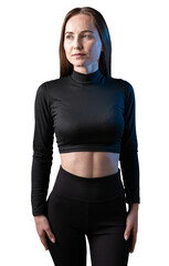 A young healthy girl in a sports top and leggings poses in the studio against a black background.