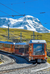 Historical photograph of an electric railcar departing from Zermatt ascending to Gornergrat (Valais, Switzerland). Train of the famous cog railway on the route above the tree line in summer.