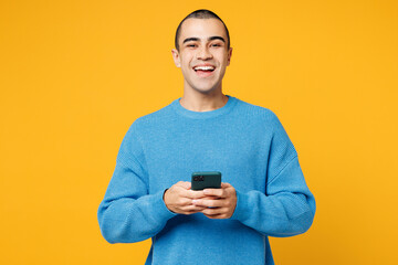 Young happy middle eastern man wearing blue sweatshirt casual clothes hold in hand use mobile cell...