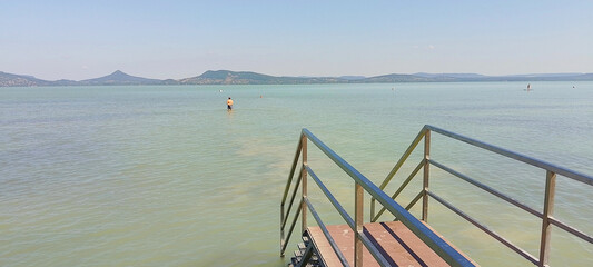 Wooden pier and reeds along the shore of Lake Balaton on a sunny summer morning