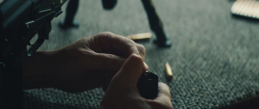 Hands loading bullet into magazine during shooting session on range outdoors