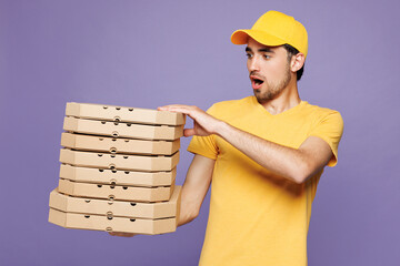 Young shocked delivery guy employee man wear yellow cap t-shirt uniform workwear work as dealer...