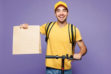 Young fun delivery guy employee man wears yellow cap t-shirt uniform workwear thermal bag work as...