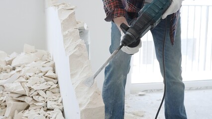 Close up of unknown male construction worker wearing red checkered shirt jeans and protective...