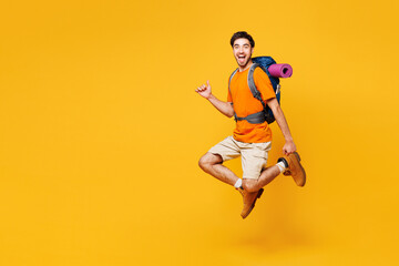Sideways young traveler man carry backpack with stuff mat jump high isolated on plain yellow background. Tourist leads active healthy lifestyle walk on spare time Hiking trek rest travel trip concept