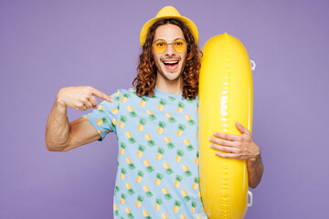 Young surprised shocked man wear blue beach t-shirt yellow hat sunglasses rest near hotel pool hold...