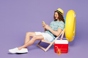 Full body young man wears blue beach t-shirt yellow hat sunglasses rest near hotel pool sit in deck...