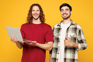 Young two friends buddies IT men they wearing casual clothes together hold use work on laptop pc...