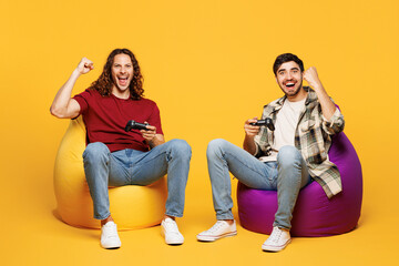 Full body winner young two friends buddies men they wear casual clothes together sit in bag chair...