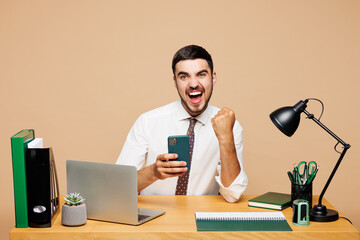 Young employee business man he wear white shirt tie sit work at office desk with pc laptop hold use...