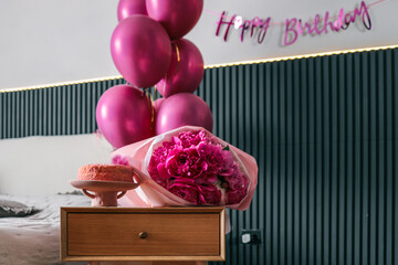 Birthday celebration setup in a bedroom with pink balloons, fresh peonies bouquet, and a pink cake...