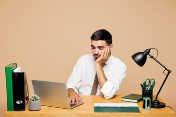 Young bored sad successful employee IT business man he wear white shirt tie sit work at office desk...