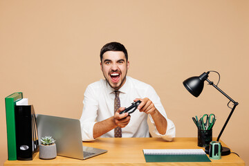 Young gamer employee business man wears white shirt tie sit work at office desk with pc laptop hold...