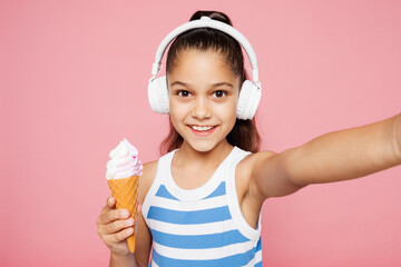 Traveler kid child wear blue casual clothes eat ice-cream do selfie isolated on plain pink...