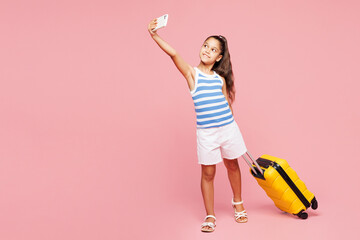Traveler kid child wear casual clothes hold bag do mobile cell phone selfie isolated on plain pink...
