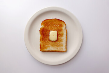 A slice of toasted bread and butter sits on a round plate.