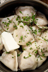Closeup of boiled dumplings with butter and chopped herbs