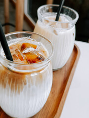 Refreshing iced drinks served in clear glasses on a wooden tray at a cozy cafe