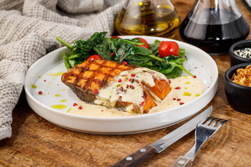 Grilled fish fillet with vegetables and creamy sauce on plate
