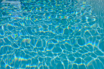 blue blurred textured swimming pool water surface waving motion by wind blow at noon sunshine